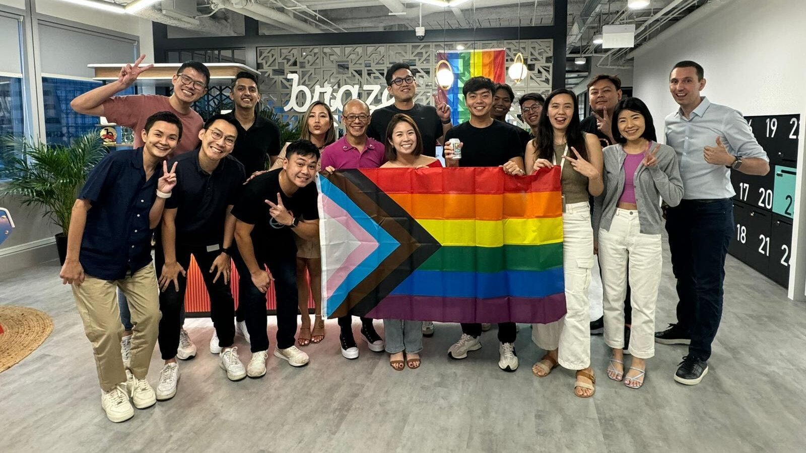 Members of the Pride@Braze ERG pose for a group photo in Braze’s Singapore office, holding a pride flag.  