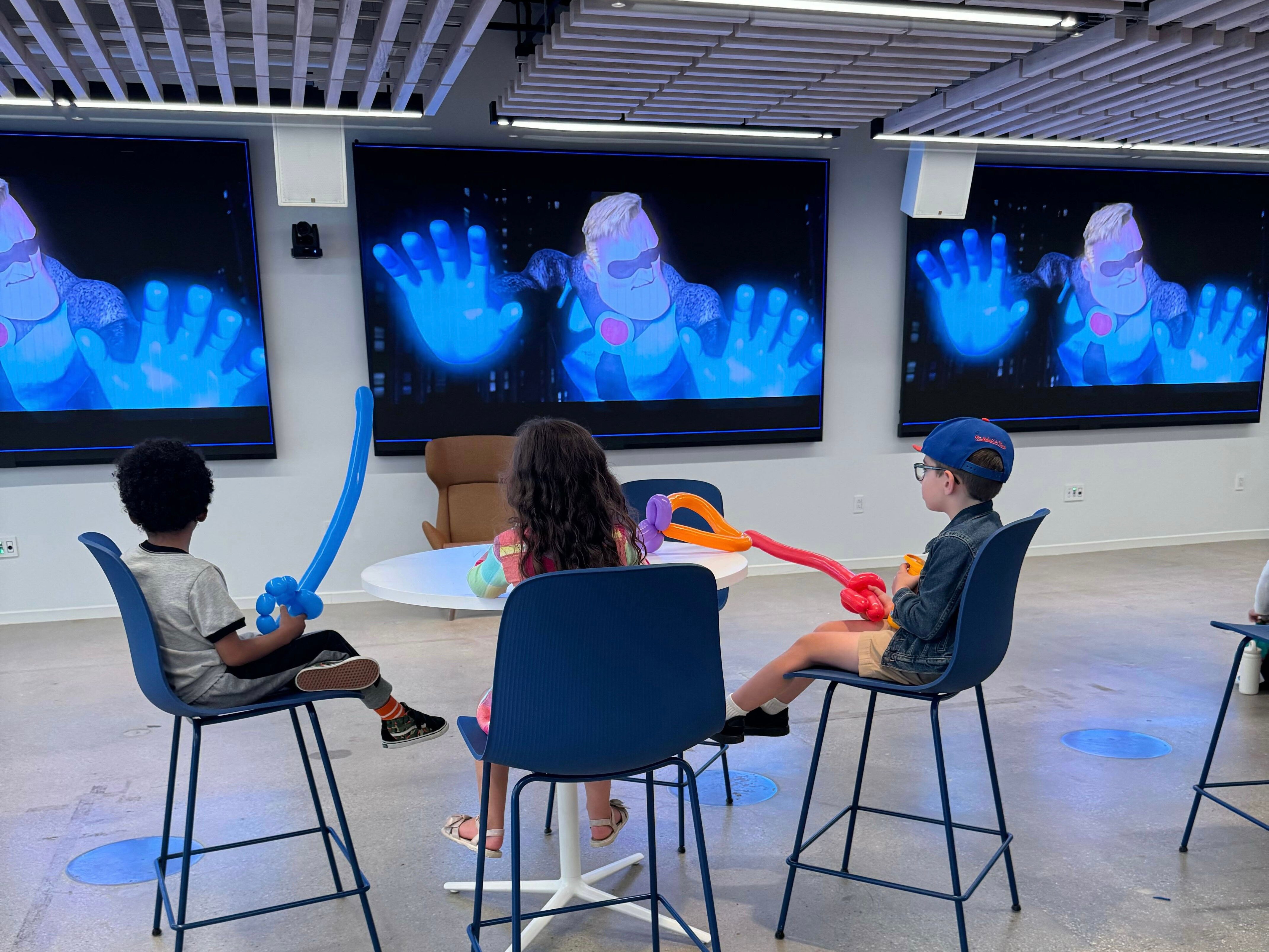 Children sit with balloon animals and watch The Incredibles during Braze’s Take Your Kids to Work Day celebrations.