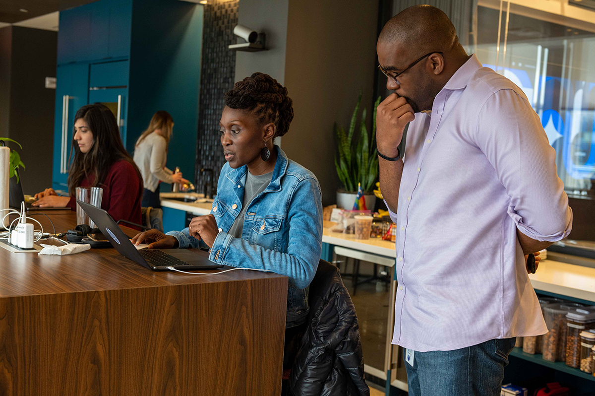 Two Coinbase team members in the office looking at a laptop