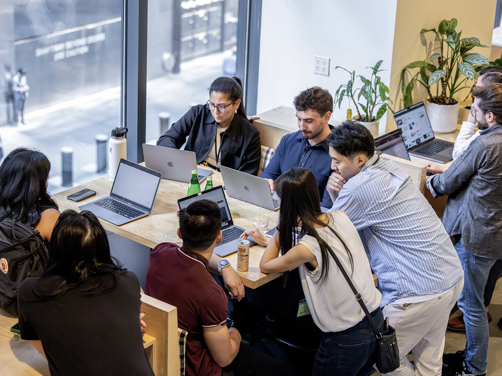 Narmi employees work closely together on their laptops at a shared table in the office.