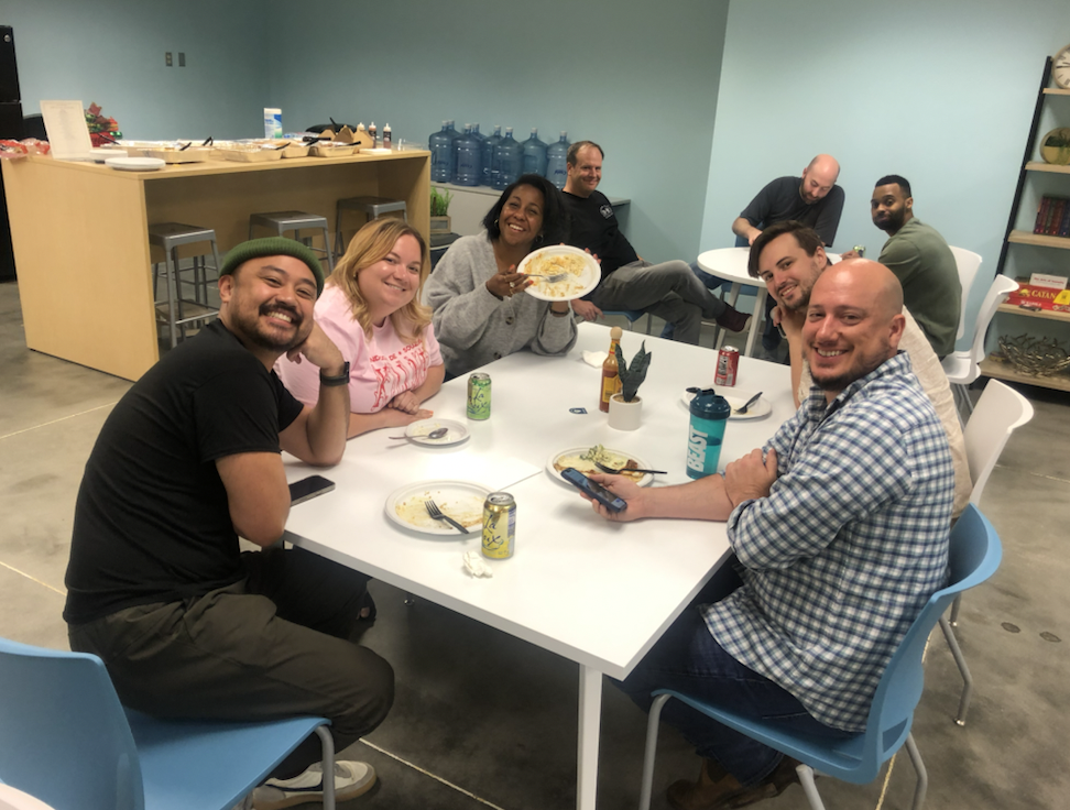 Photo of smiling Petal employees gathering for lunch around a table in the office kitchen.