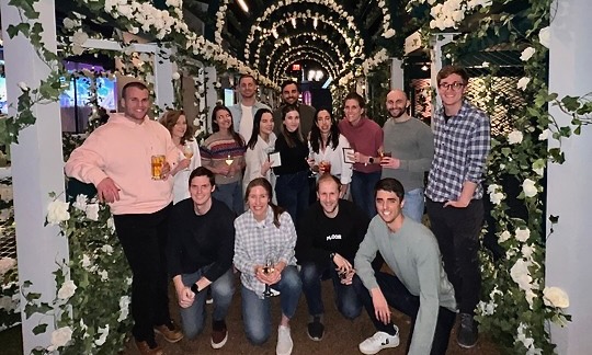 The account management team at Riskified pose for a group photo under flowery arches at an outing.