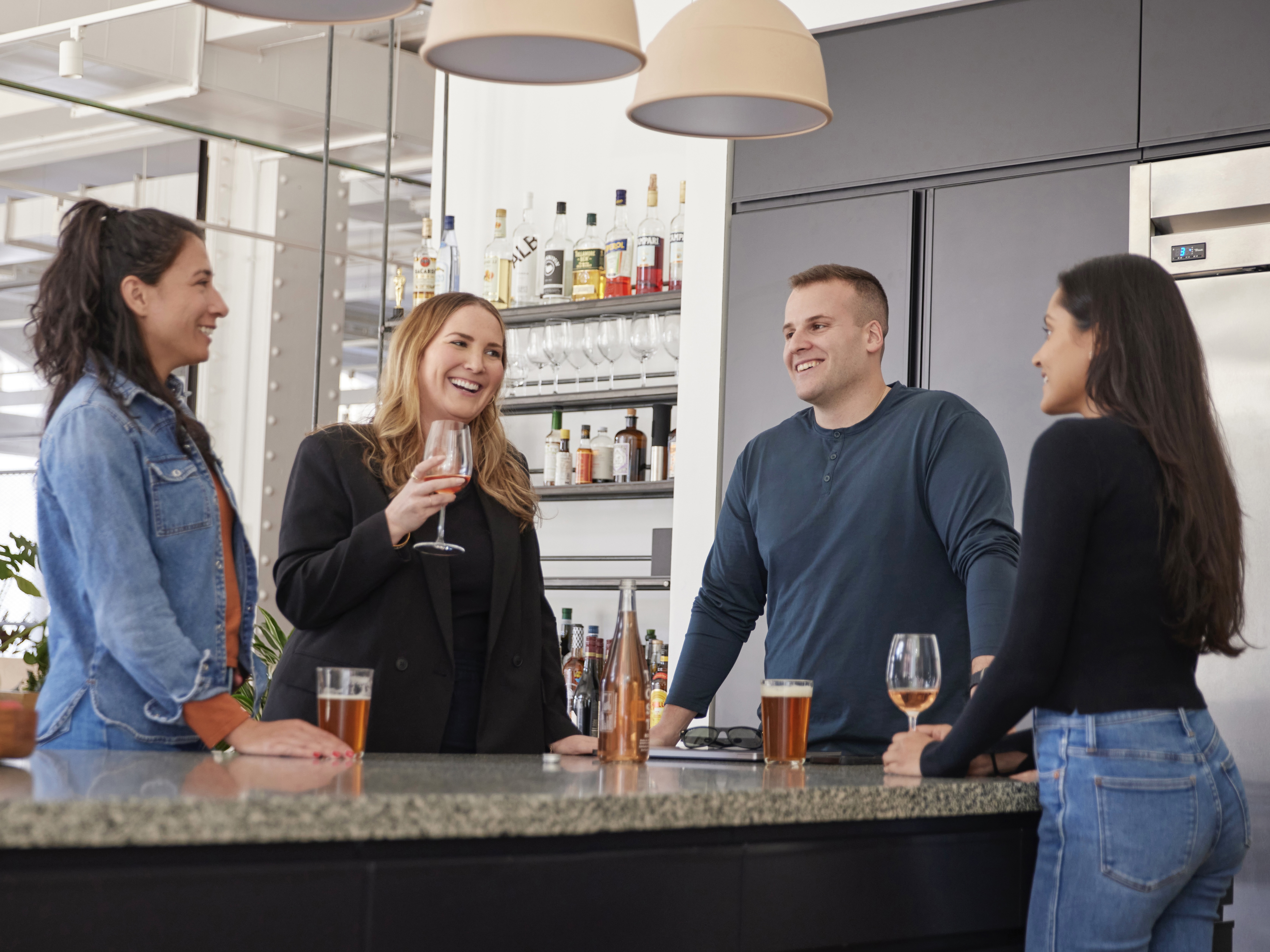 Riskified employees stand together in the office kitchen and catch up over wine and beer.