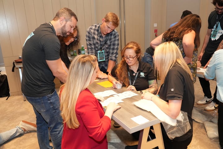 Team members gather around a small workbench looking at paper together