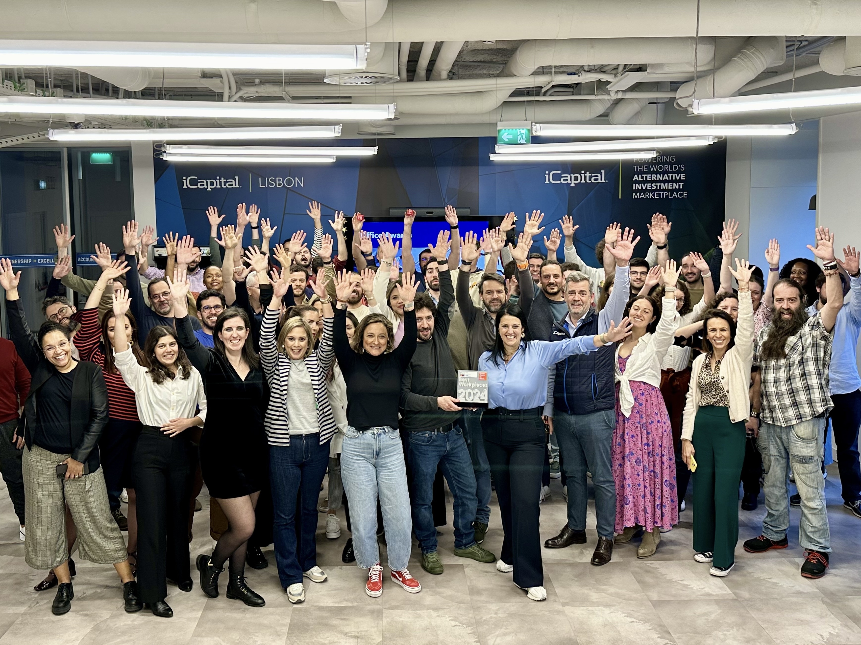 iCapital employees raise their hands in celebration in their Lisbon office.