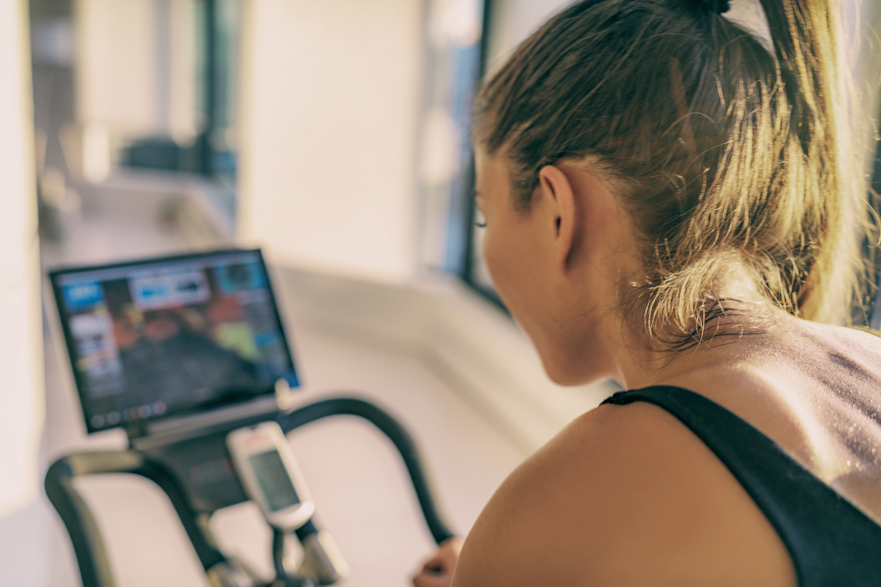 A woman seated on a Peloton stationary cycle